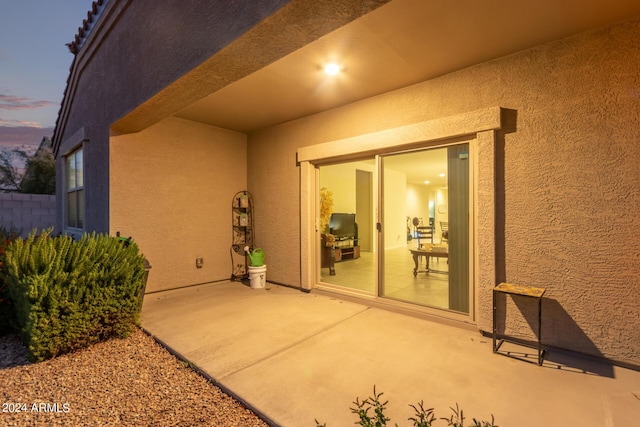 exterior entry at dusk featuring a patio