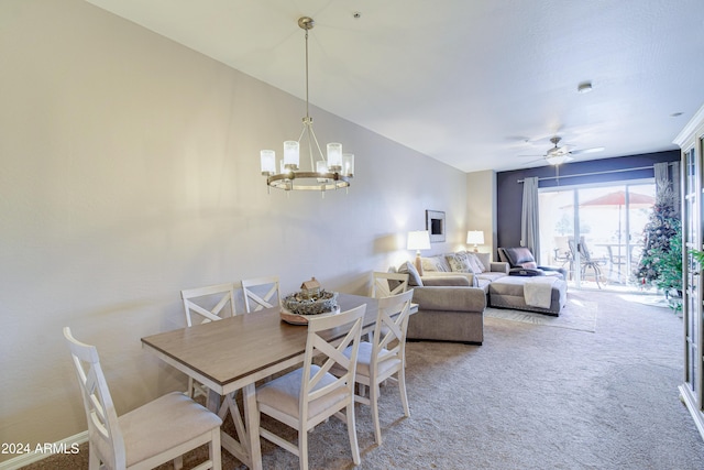 carpeted dining area featuring ceiling fan with notable chandelier