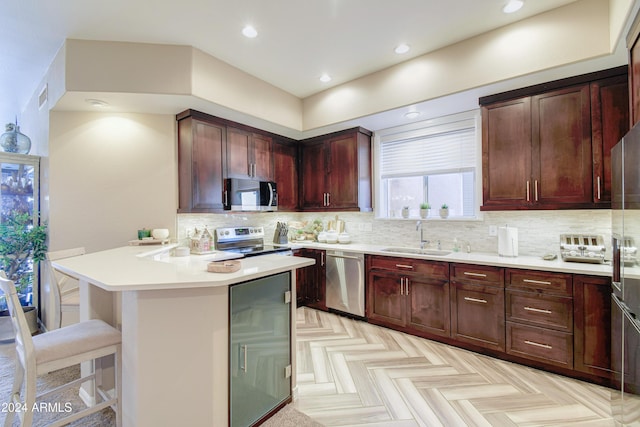 kitchen featuring decorative backsplash, stainless steel appliances, a breakfast bar area, and sink