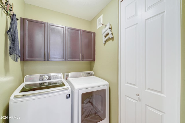 laundry room featuring separate washer and dryer and cabinets