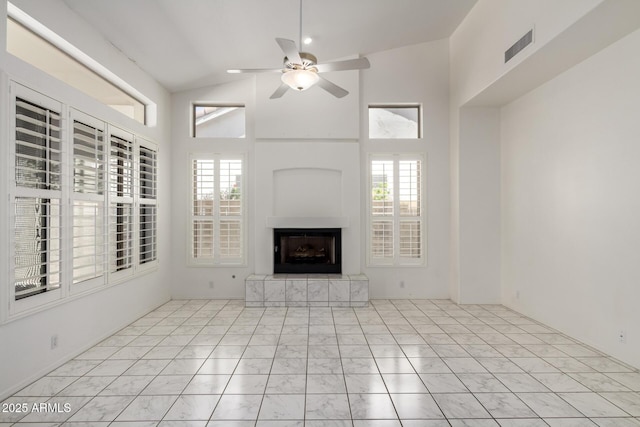 unfurnished living room with ceiling fan, a fireplace with raised hearth, marble finish floor, and a wealth of natural light