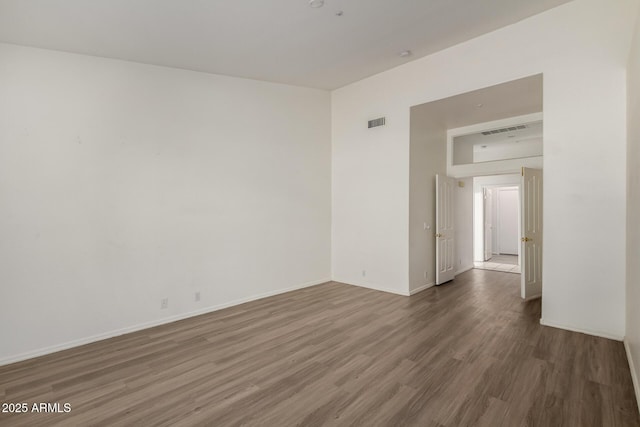 empty room featuring visible vents, baseboards, and wood finished floors
