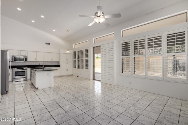 kitchen with dark countertops, appliances with stainless steel finishes, visible vents, white cabinetry, and vaulted ceiling