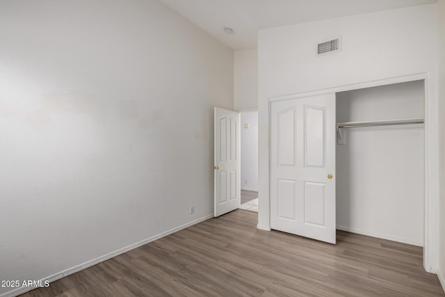 unfurnished bedroom featuring baseboards, wood finished floors, and visible vents