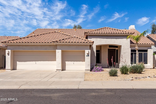 mediterranean / spanish home with a tiled roof, a garage, stucco siding, and driveway