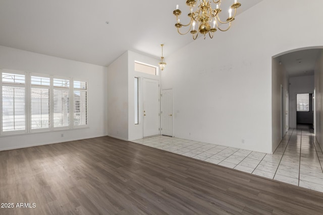 interior space featuring arched walkways, wood finished floors, a chandelier, and high vaulted ceiling