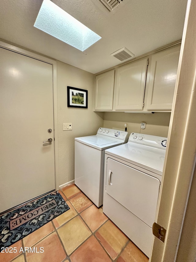 laundry room with a skylight, cabinets, washer and clothes dryer, and light tile patterned floors