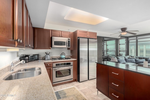 kitchen featuring a ceiling fan, light stone counters, stainless steel appliances, a sink, and light tile patterned flooring