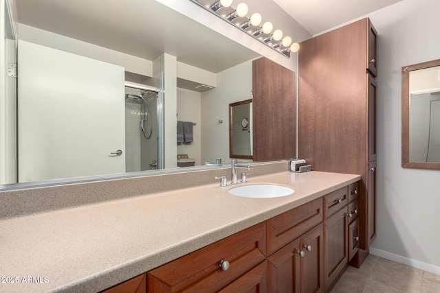 bathroom featuring tile patterned flooring, baseboards, a tile shower, and vanity