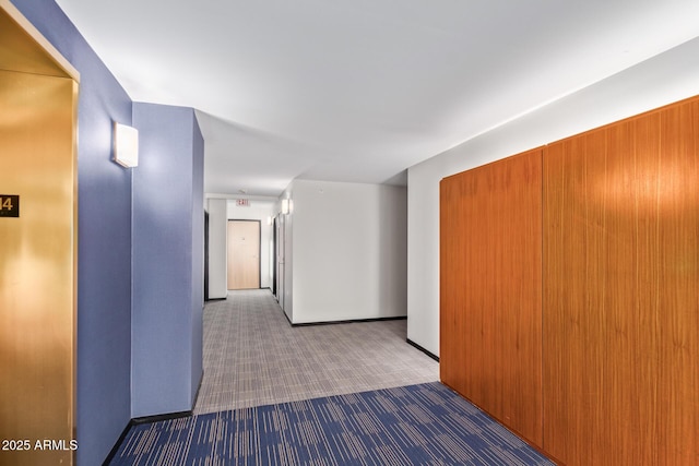 corridor featuring baseboards and carpet flooring