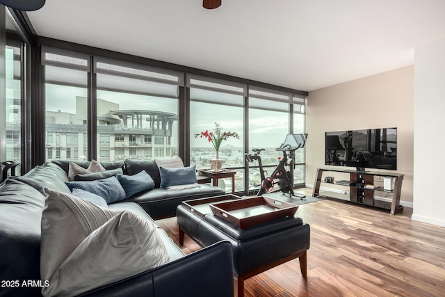 living room featuring a wall of windows, baseboards, and wood finished floors