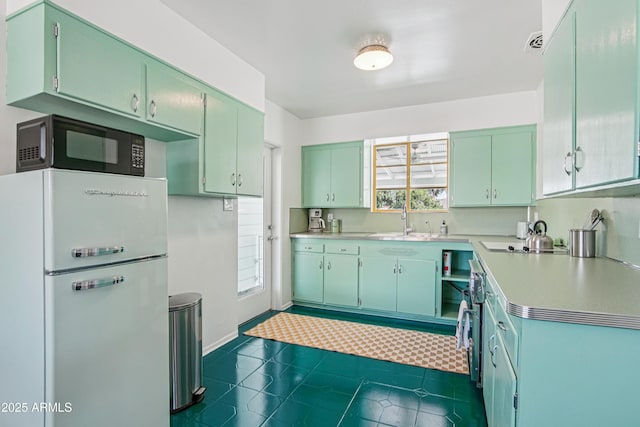805 E Jackson Ave, Buckeye, AZ 85326 - kitchen featuring freestanding refrigerator, black microwave, light countertops, dark tile patterned floors, and baseboards