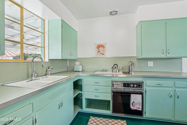 805 E Jackson Ave, Buckeye, AZ 85326 - kitchen with black oven, a sink, light countertops, and cooktop