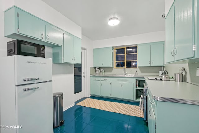 805 E Jackson Ave, Buckeye, AZ 85326 - kitchen featuring black appliances, a sink, light countertops, dark tile patterned floors, and baseboards