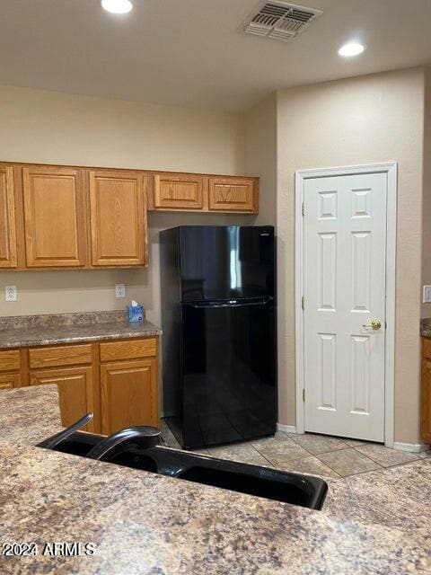 kitchen with black refrigerator, light tile patterned flooring, and sink