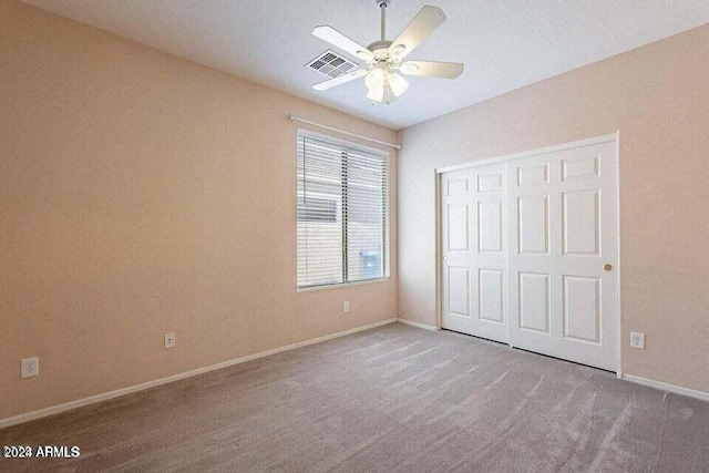 unfurnished bedroom featuring ceiling fan, a closet, and light carpet