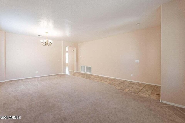 unfurnished room featuring carpet, a chandelier, and a textured ceiling