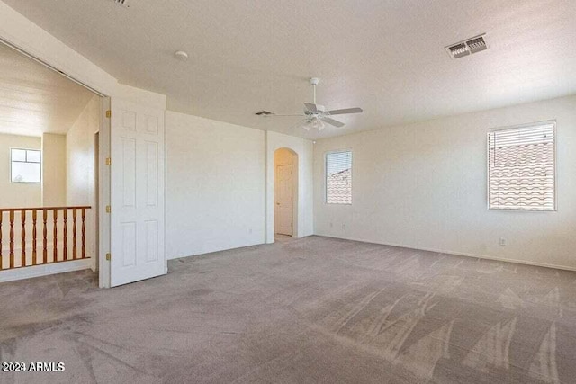 spare room featuring carpet flooring, ceiling fan, a healthy amount of sunlight, and a textured ceiling