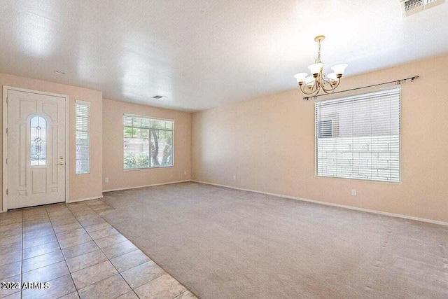 entryway with light carpet, a textured ceiling, and a notable chandelier