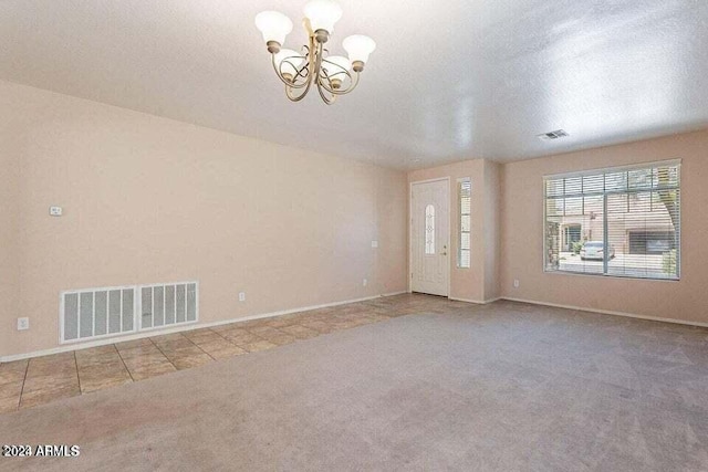 unfurnished room with light carpet, a textured ceiling, and a notable chandelier