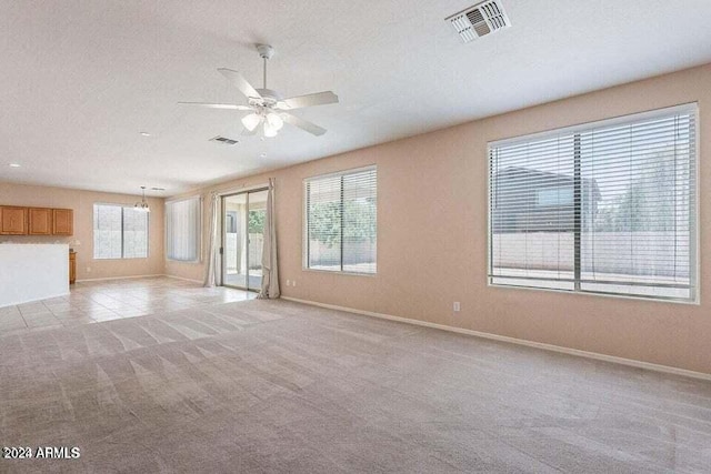 unfurnished living room with a textured ceiling, light colored carpet, and ceiling fan