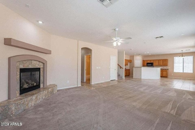 unfurnished living room featuring light carpet, a textured ceiling, a fireplace, and ceiling fan