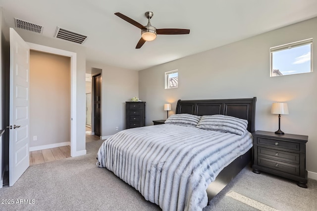 bedroom with baseboards, visible vents, and light carpet