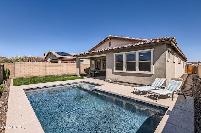 back of house with a fenced in pool, a tiled roof, stucco siding, a fenced backyard, and a patio