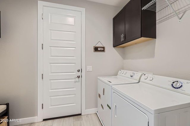 washroom featuring light wood-style flooring, cabinet space, independent washer and dryer, and baseboards