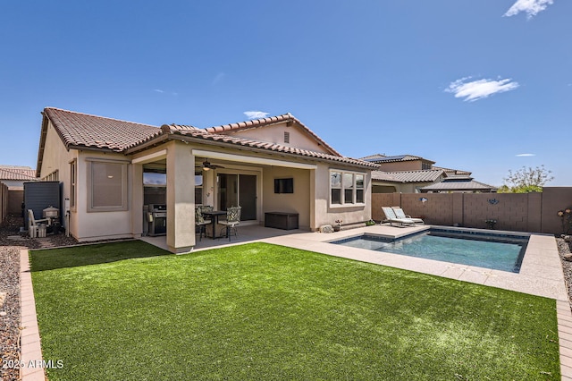 rear view of property with ceiling fan, stucco siding, a yard, a fenced backyard, and a patio area