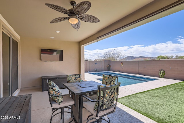 view of patio / terrace with a fenced in pool, outdoor dining area, a fenced backyard, and a ceiling fan