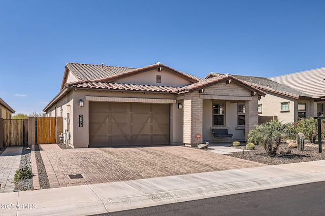 view of front of home with a gate, decorative driveway, fence, a garage, and a tiled roof