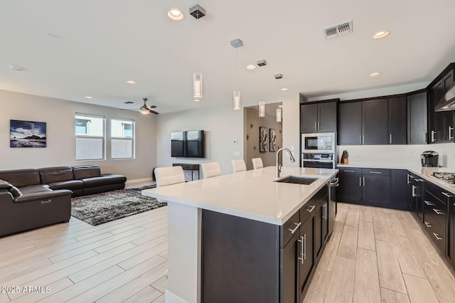 kitchen featuring visible vents, open floor plan, light countertops, stainless steel appliances, and a sink