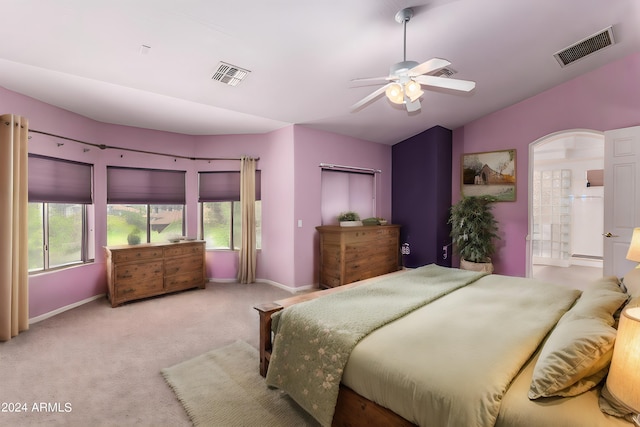 carpeted bedroom featuring ceiling fan, ensuite bath, and lofted ceiling