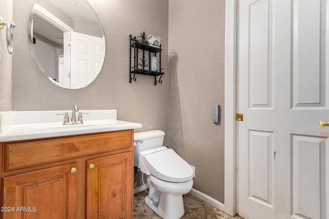 half bath featuring baseboards, toilet, and vanity