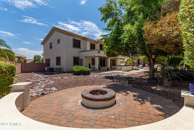 back of property featuring a fire pit, fence, central AC, stucco siding, and a patio area