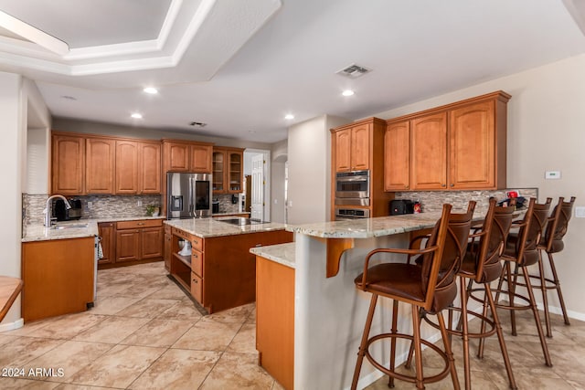 kitchen with appliances with stainless steel finishes, light tile patterned floors, a center island, tasteful backsplash, and sink