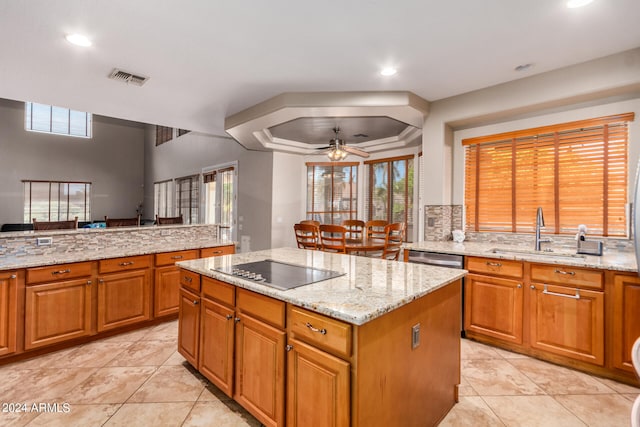 kitchen with ceiling fan, a tray ceiling, light tile patterned floors, and black electric cooktop