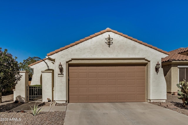 mediterranean / spanish-style home with an attached garage, driveway, a tiled roof, and stucco siding