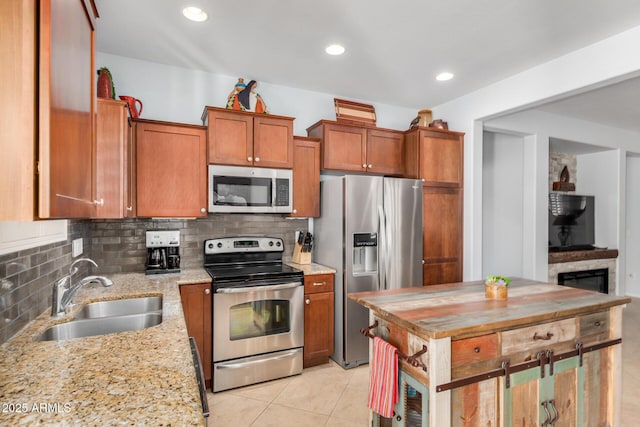 kitchen with stainless steel appliances, tasteful backsplash, a sink, and brown cabinets