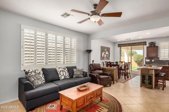 living room with ceiling fan, visible vents, and light tile patterned flooring