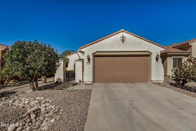 mediterranean / spanish home with driveway, a garage, a tiled roof, a gate, and stucco siding