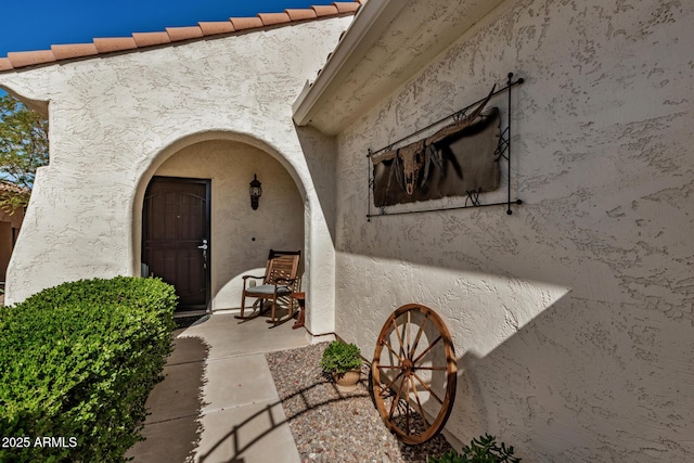 view of exterior entry featuring a tile roof and stucco siding