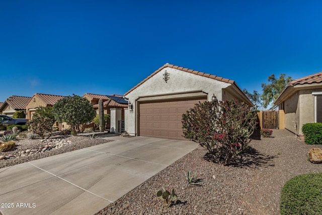 view of front of home featuring a tile roof, stucco siding, an attached garage, fence, and driveway