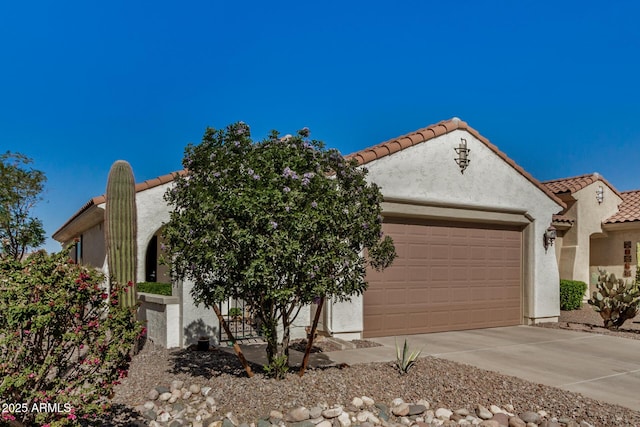 mediterranean / spanish-style home featuring an attached garage, a tiled roof, concrete driveway, and stucco siding