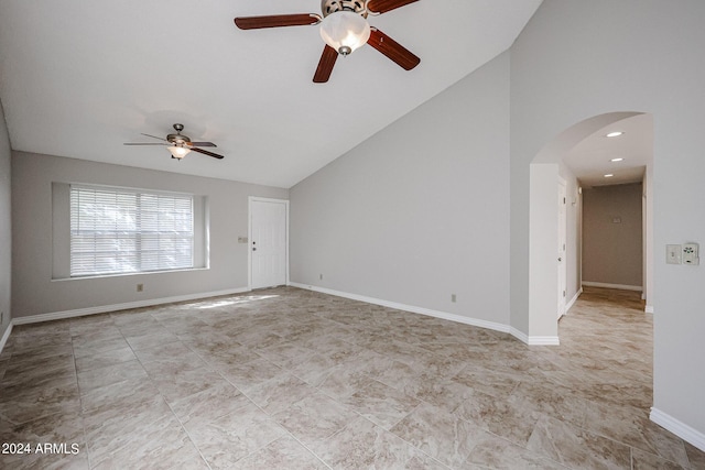 empty room with arched walkways, high vaulted ceiling, ceiling fan, and baseboards