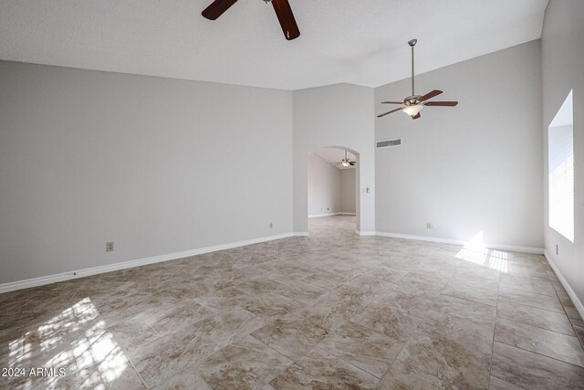 tiled spare room with a textured ceiling and vaulted ceiling