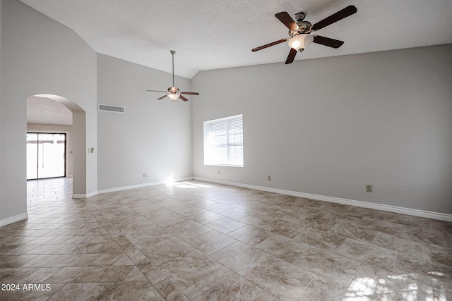 spare room with arched walkways, a textured ceiling, a ceiling fan, visible vents, and baseboards