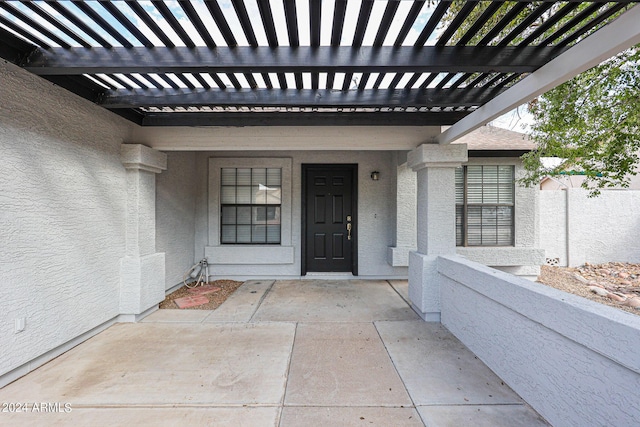 doorway to property featuring a pergola, fence, and stucco siding