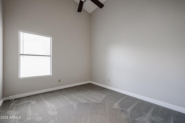 unfurnished room with vaulted ceiling, dark colored carpet, a ceiling fan, and baseboards